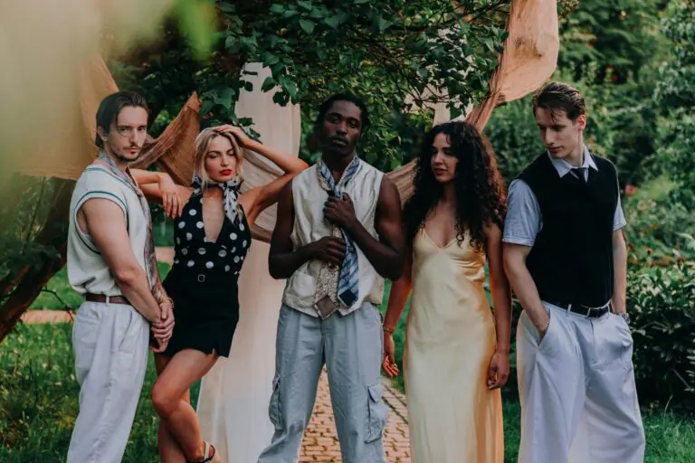 Five diverse young adults posing together in a lush garden setting with natural warmth