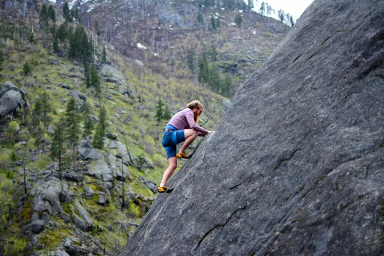 Person rock climbing on cliff face demonstrating high-intensity physical activity.