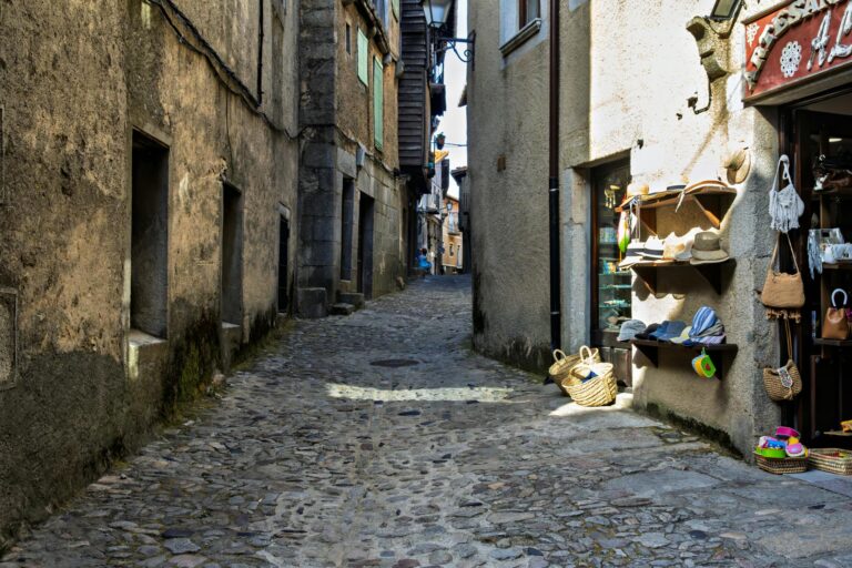 Rustic cobbled street lined with boutique shops and historic architecture in Spain.