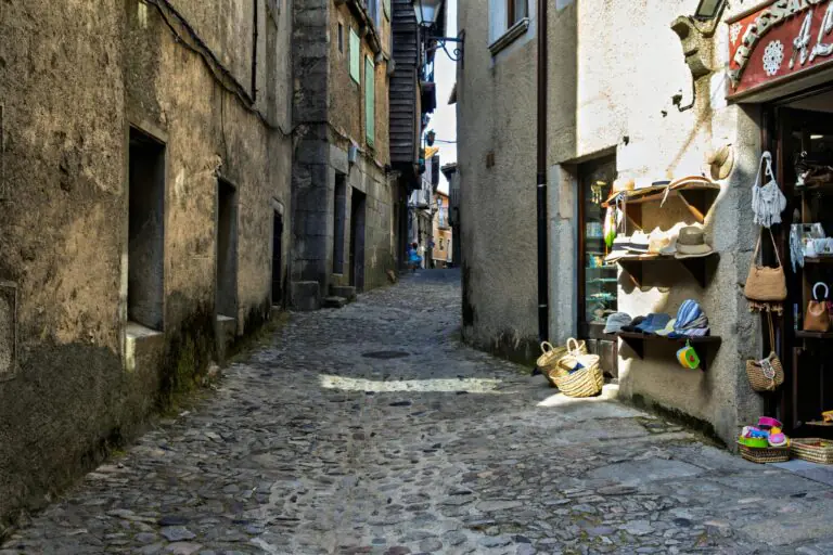 Rustic cobbled street lined with boutique shops and historic architecture in Spain.