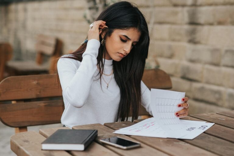 Focused young woman reviewing schedule outdoors with notebook