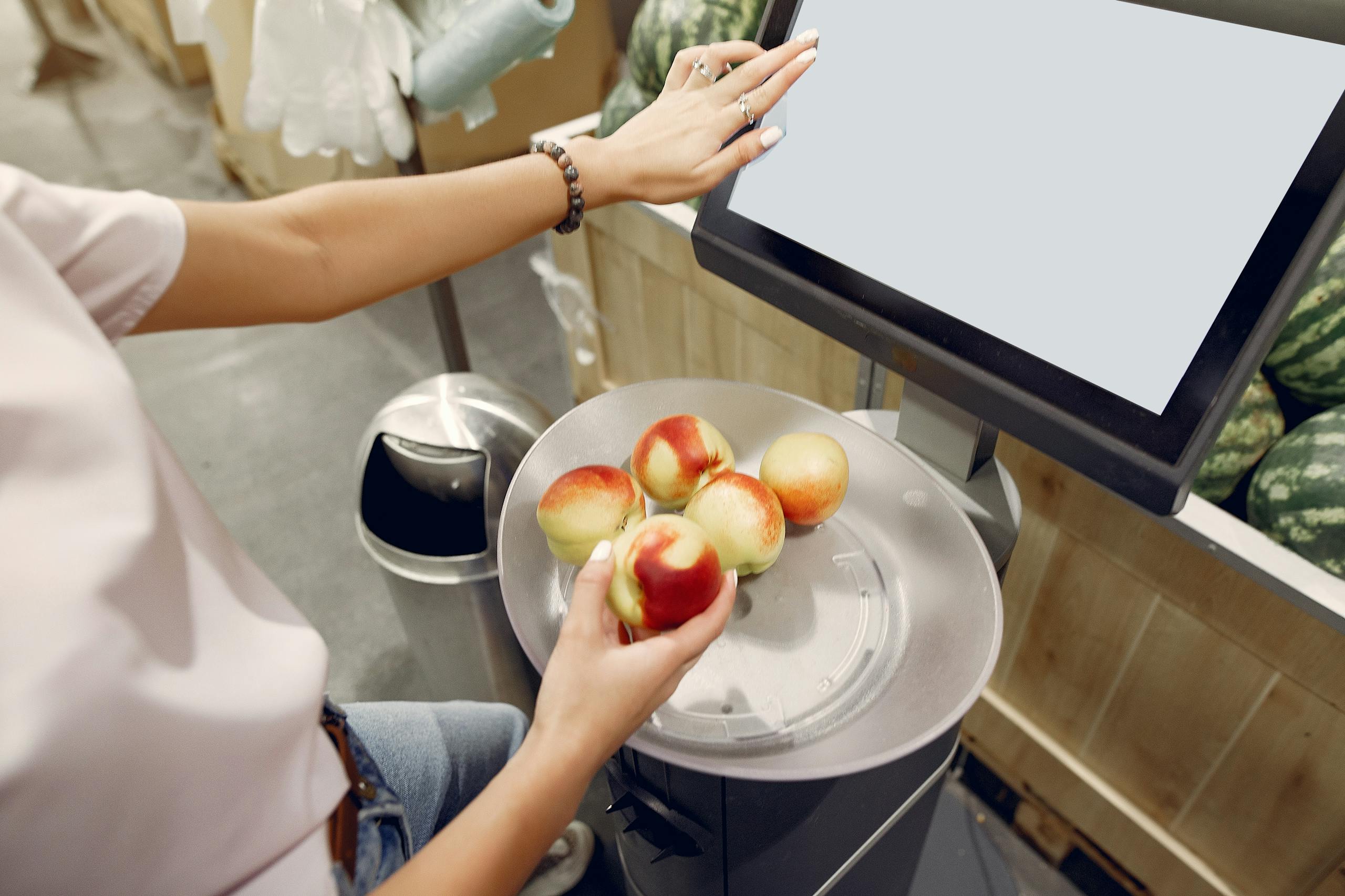 Woman carefully selecting and weighing peaches at supermarket scale