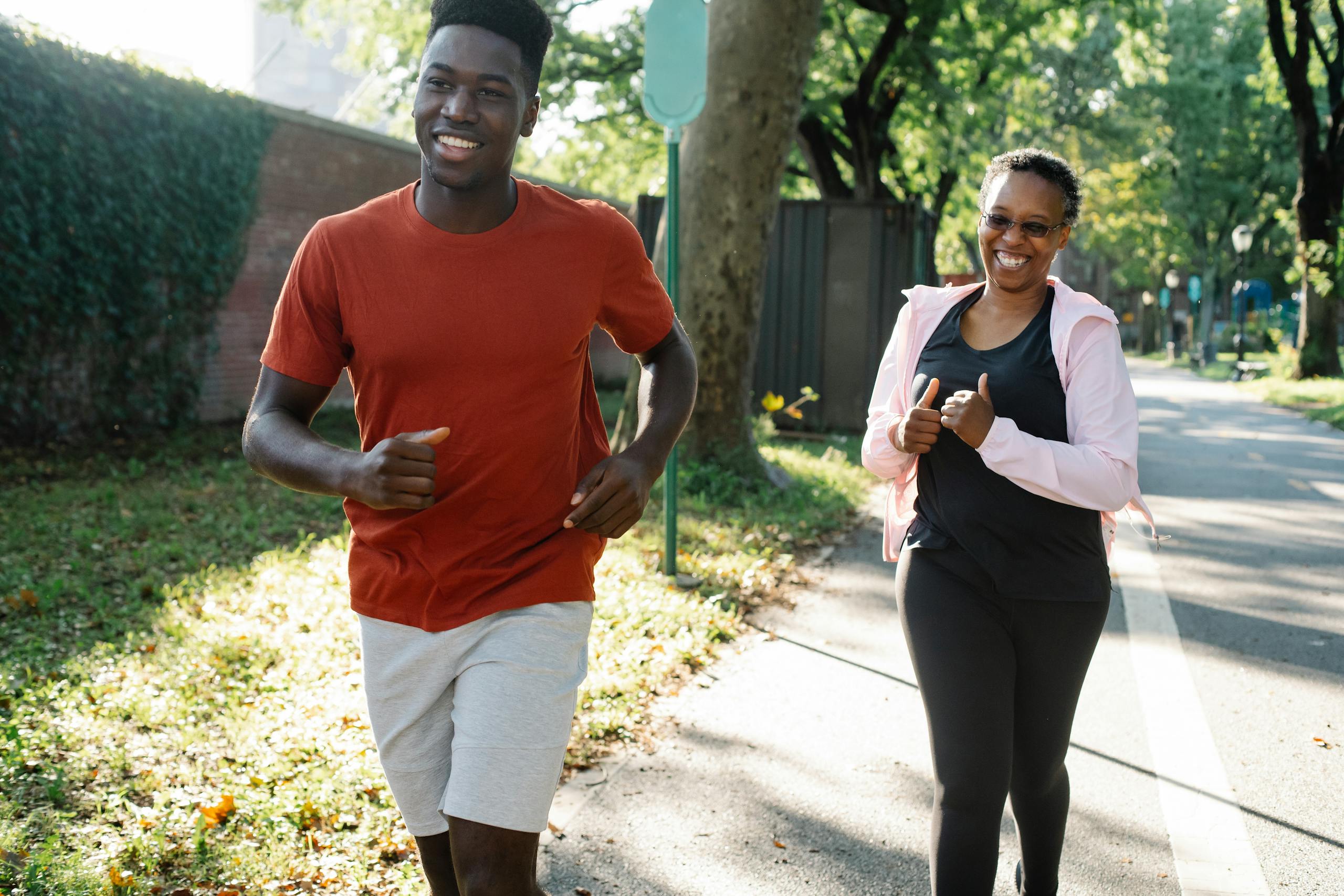 Happy couple enjoys jogging together in sunny park embracing healthy lifestyle