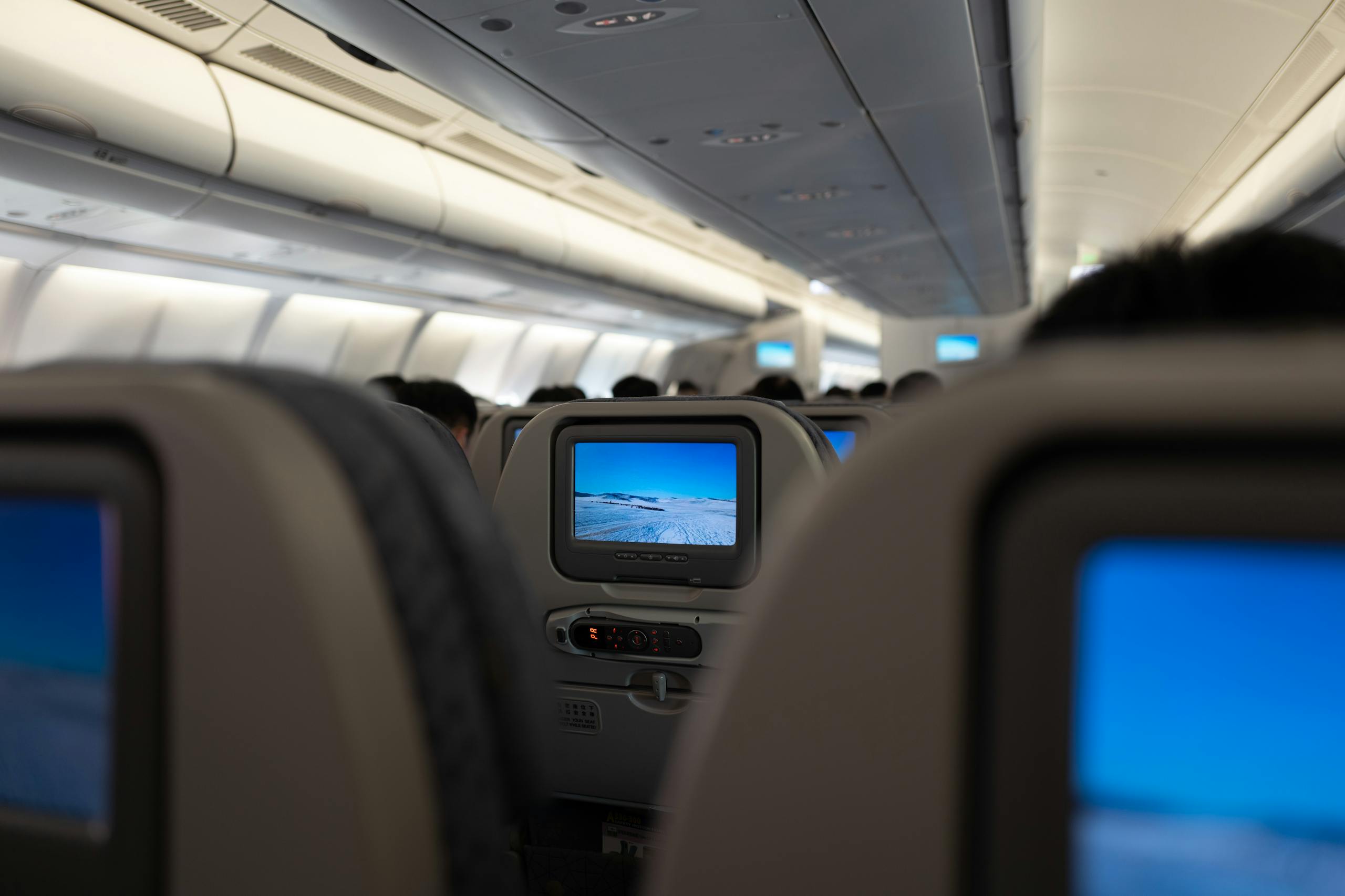 Interior airplane view with in-flight entertainment screens and passenger seats