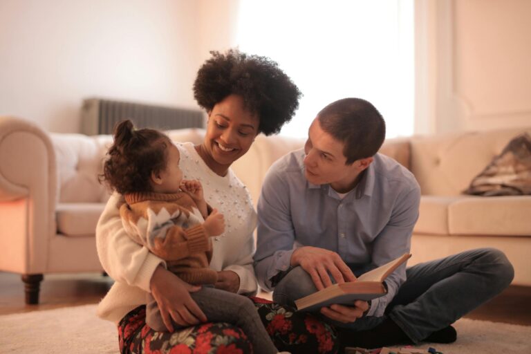 Loving parents reading with cheerful toddler in cozy living room