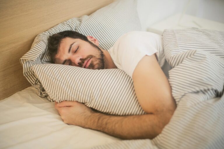 Man peacefully sleeping on striped bedding in relaxed comfortable position