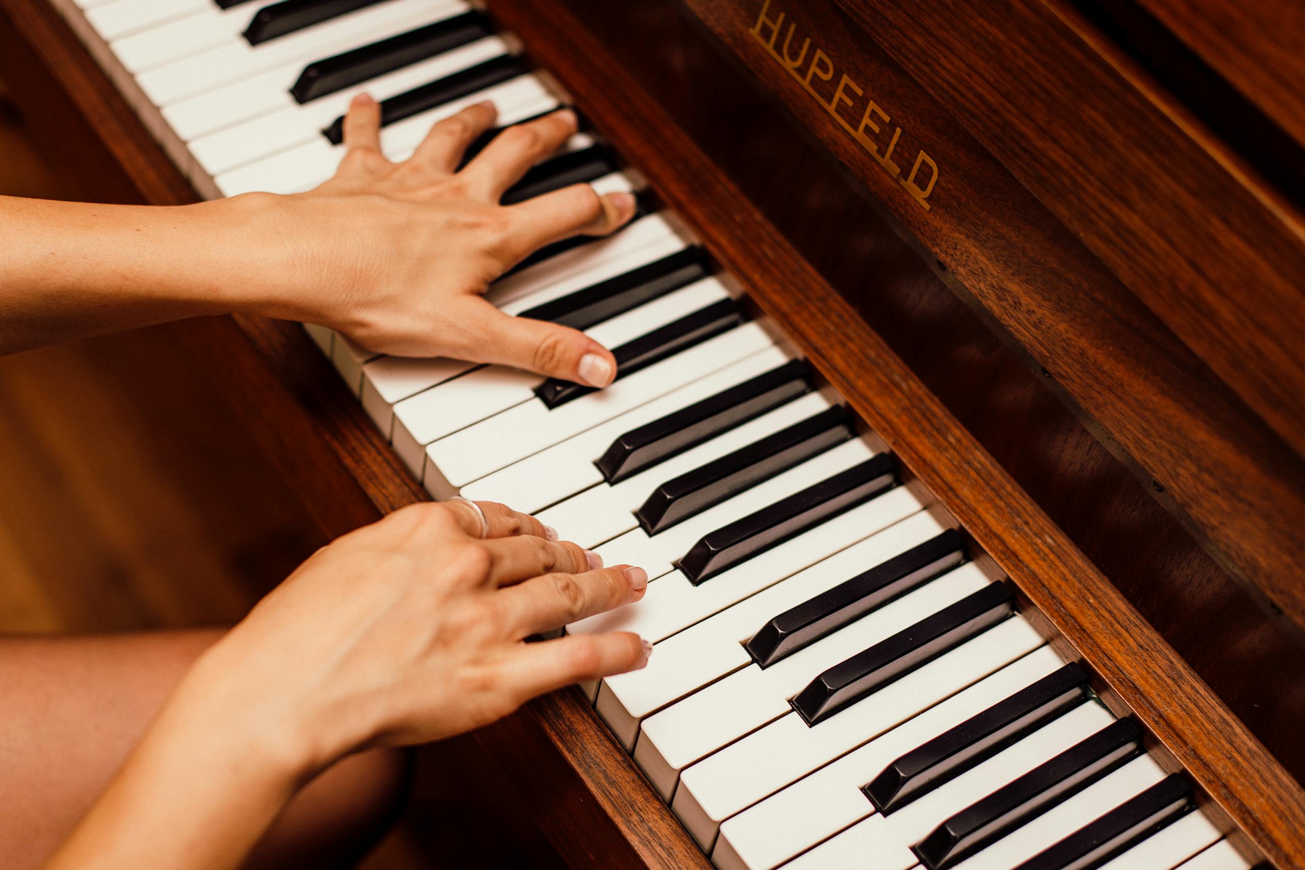 Musician's hands playing wooden piano keys in high contrast artistic shot