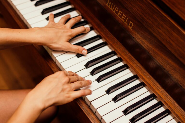 Musician's hands playing wooden piano keys in high contrast artistic shot