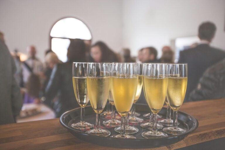 Champagne glasses arranged on table while blurred people socialize in background
