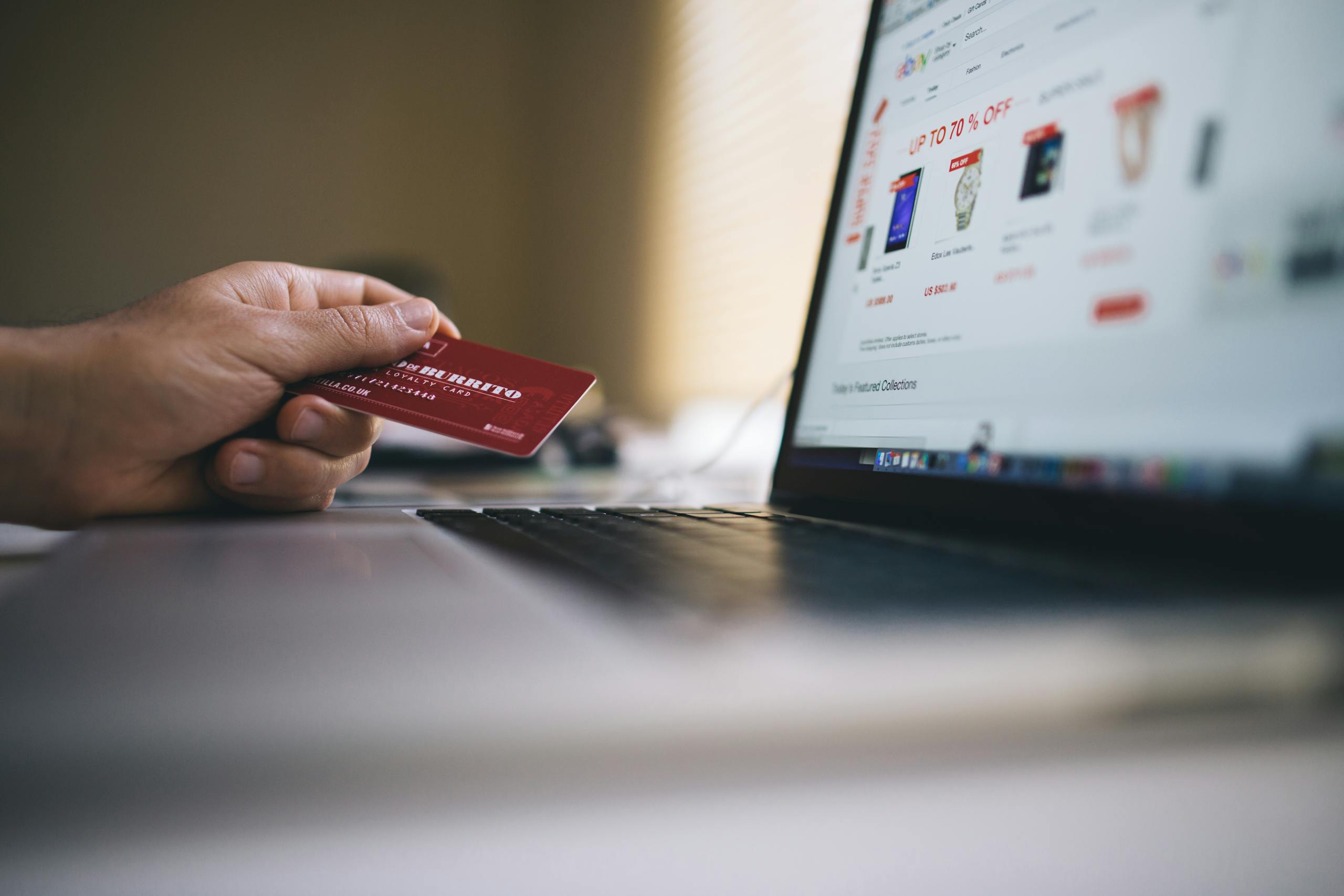 Person holding credit card while shopping online on laptop indicating digital e-commerce transaction