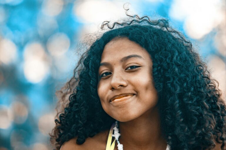 Portrait of smiling young woman with curly hair outdoors in tropical location