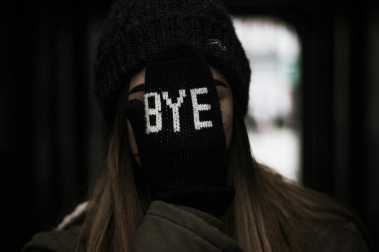 Young woman wearing hat and glove with bye text expressing playful farewell gesture.