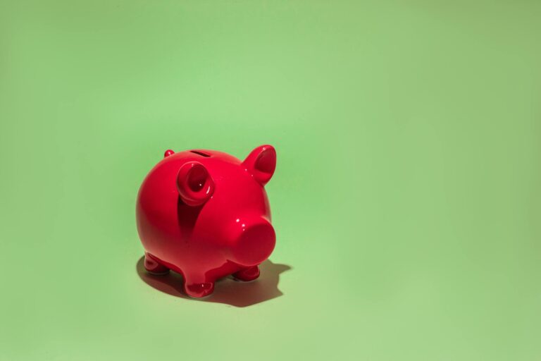 Red piggy bank on green background symbolizing savings and financial planning
