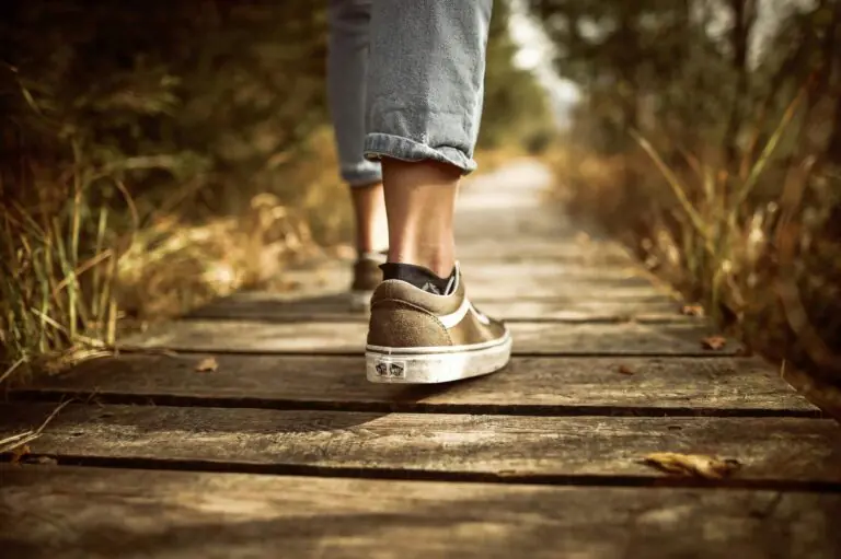 Person walking alone on wooden boardwalk through nature, solitary journey