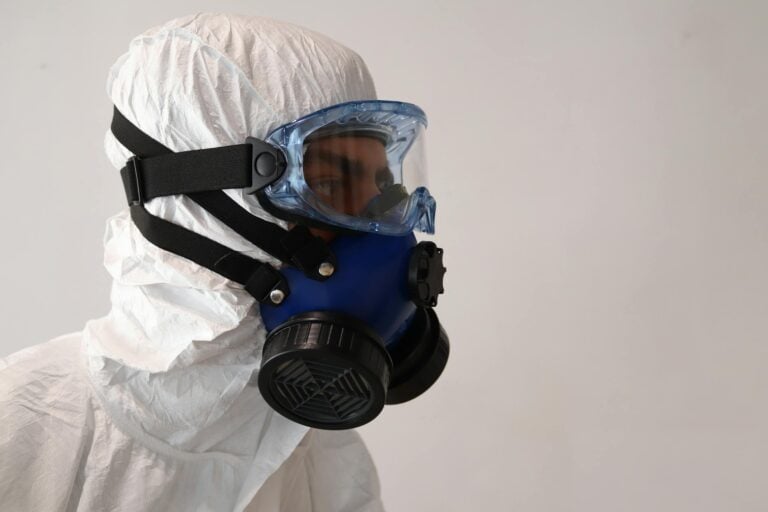 Person in protective suit wearing gas mask against white background