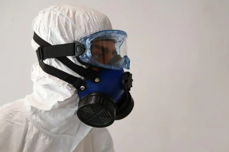 Person in protective suit wearing gas mask against white background