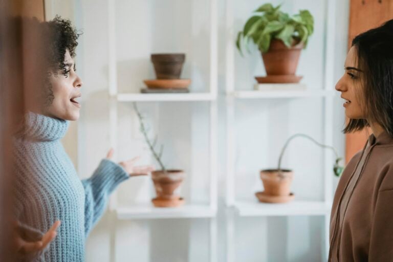 African American women in heated conflict facing each other with green plants nearby