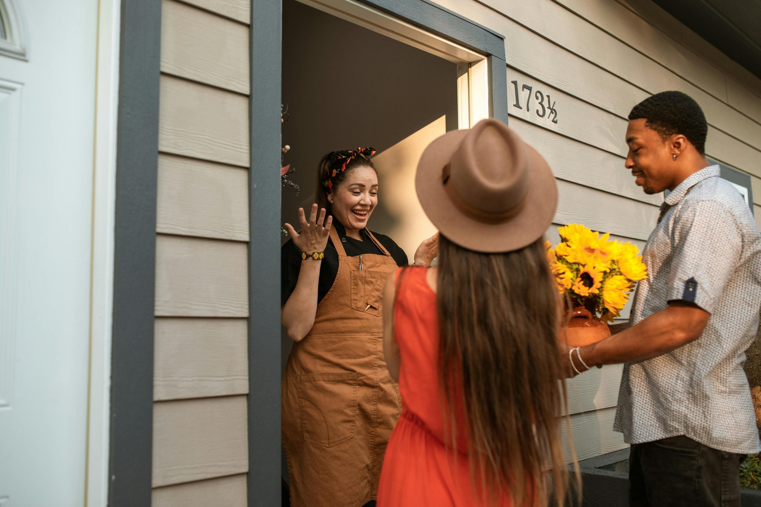 Friendly visitors greet smiling woman at doorway with sunflowers