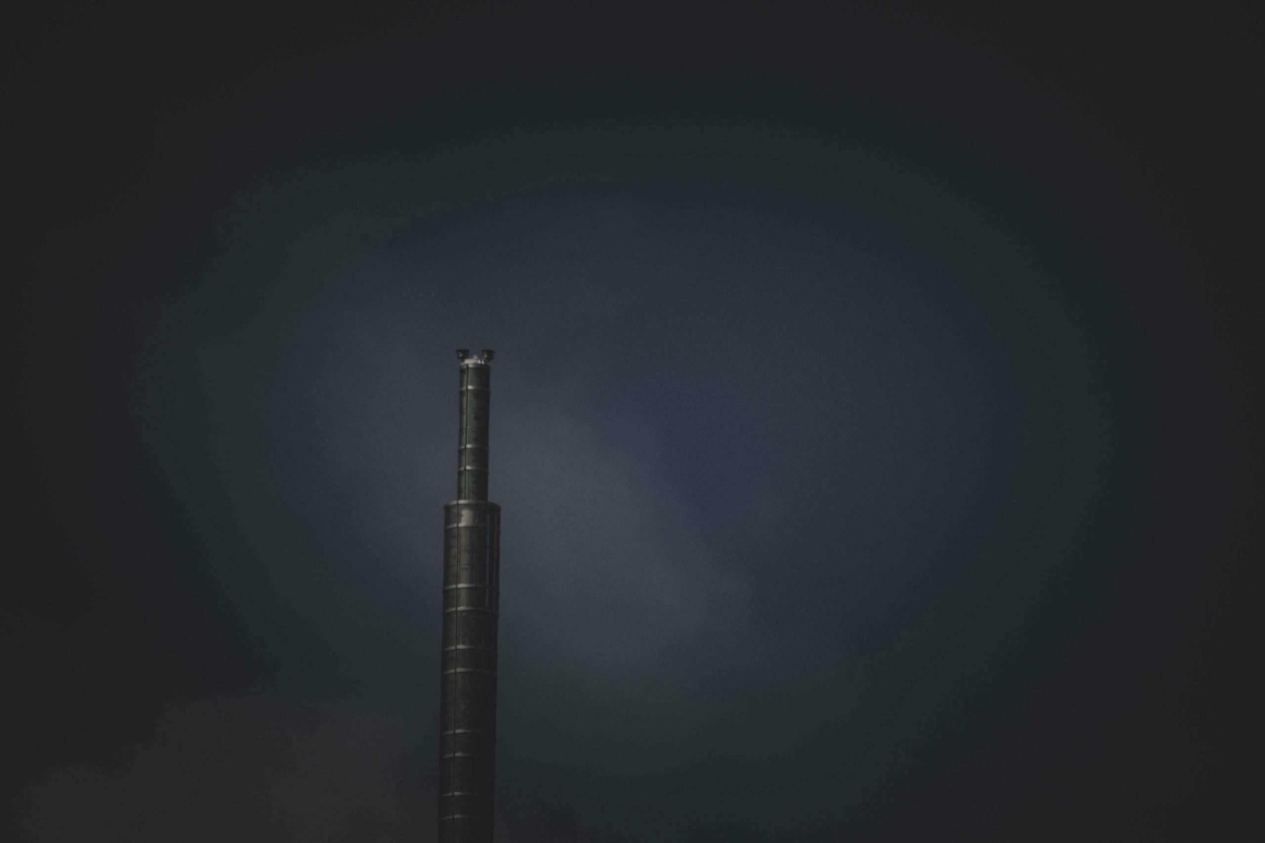 Solitary dark tower standing alone against moody twilight sky