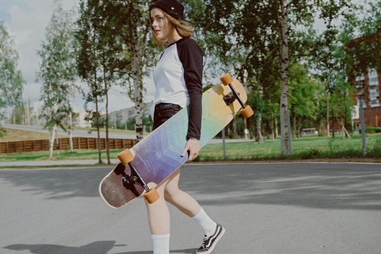 Teen girl carrying longboard skateboard in urban park enjoying outdoor leisure