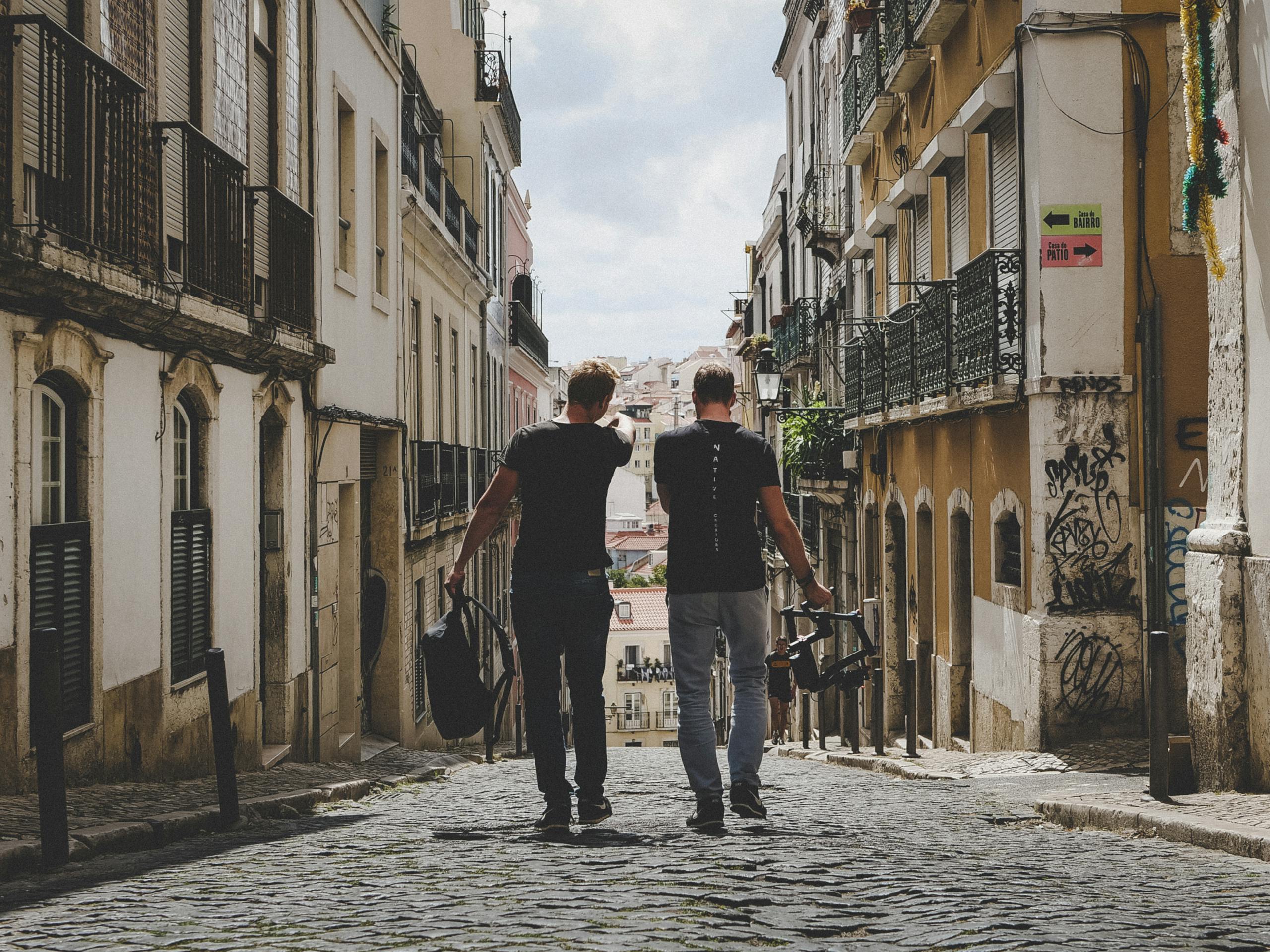 Two friends walking together through charming Lisbon cobblestone streets capturing urban vibe