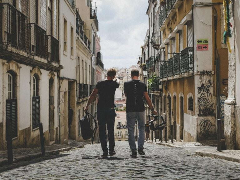 Two friends walking together through charming Lisbon cobblestone streets capturing urban vibe