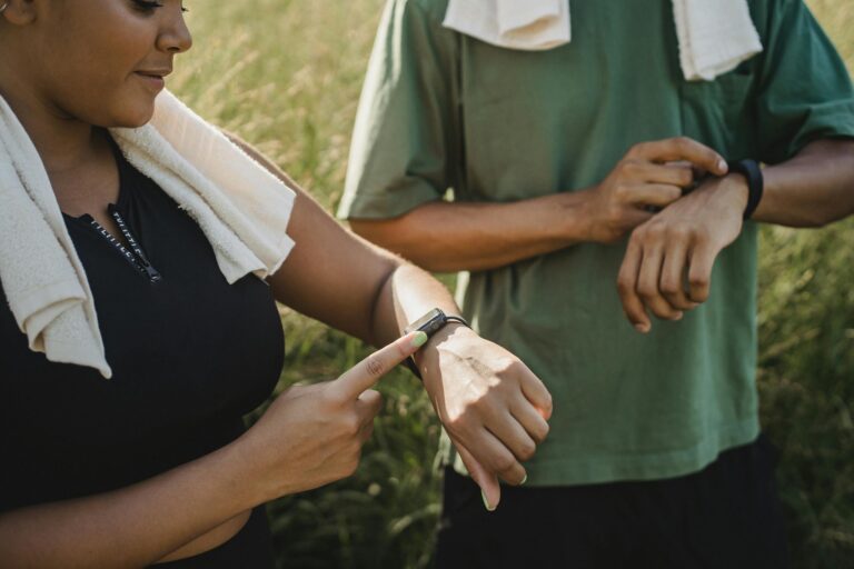 Two people checking fitness watches while taking workout break outdoors