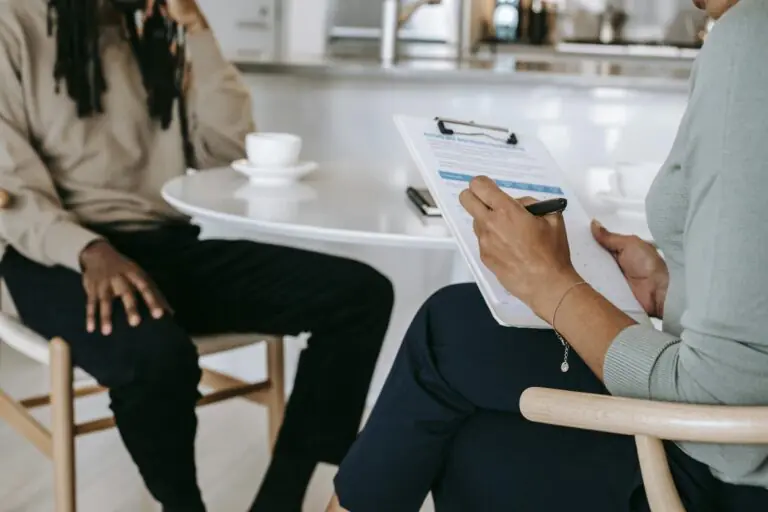 Two professionals engaged in consultation with one taking notes on clipboard