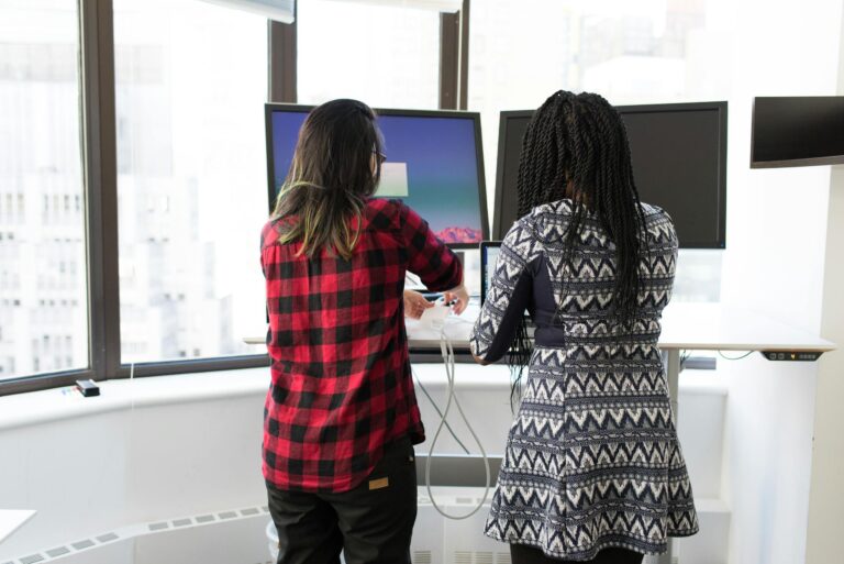Two women working together at standing desks in bright office