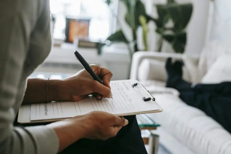 Female therapist taking notes on clipboard during psychological appointment with client