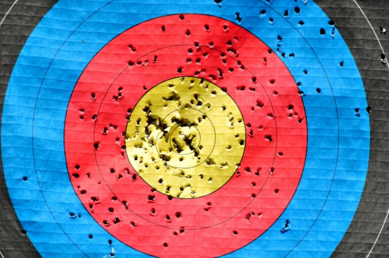 Vibrant archery target with multiple hits across colored rings showing accuracy.