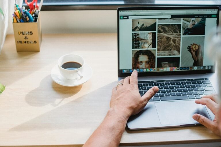 Person working on laptop with coffee, focused on creative visual content design