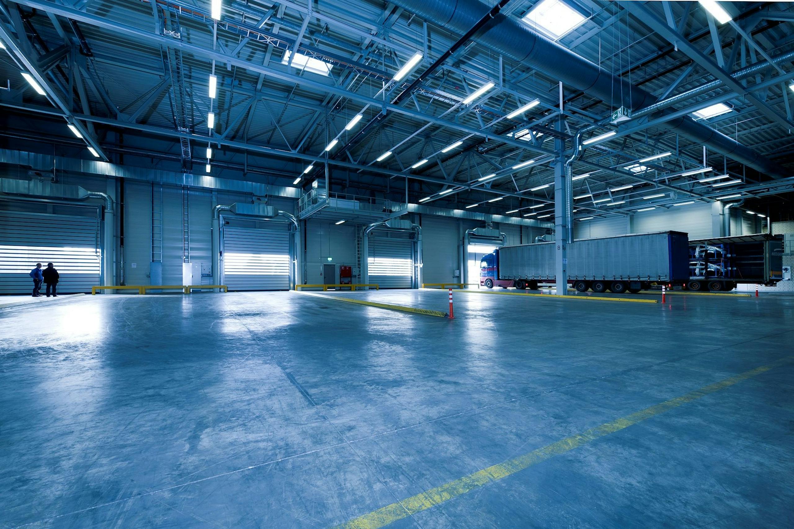 Wide view of empty modern warehouse with industrial lighting and trucks.
