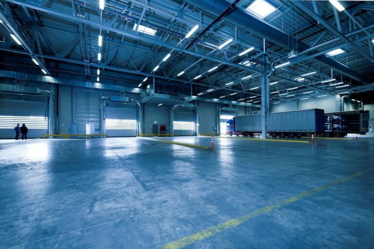 Wide view of empty modern warehouse with industrial lighting and trucks.