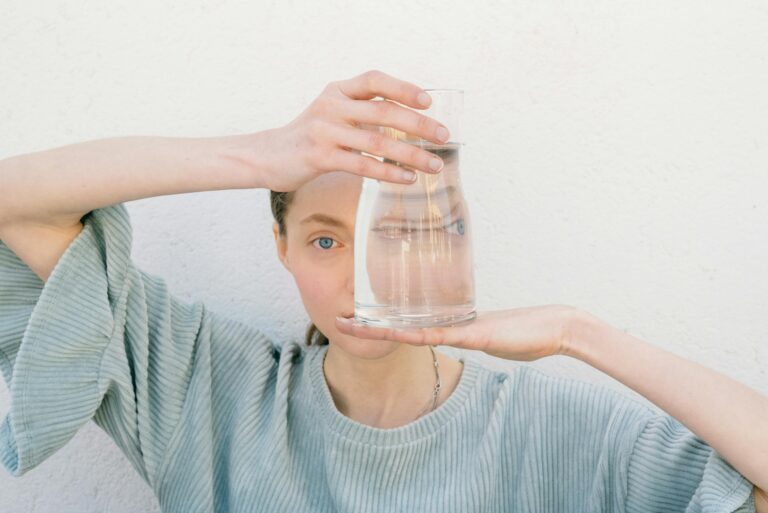 woman holding a glass jug reflecting her face creating a unique visual distortion.