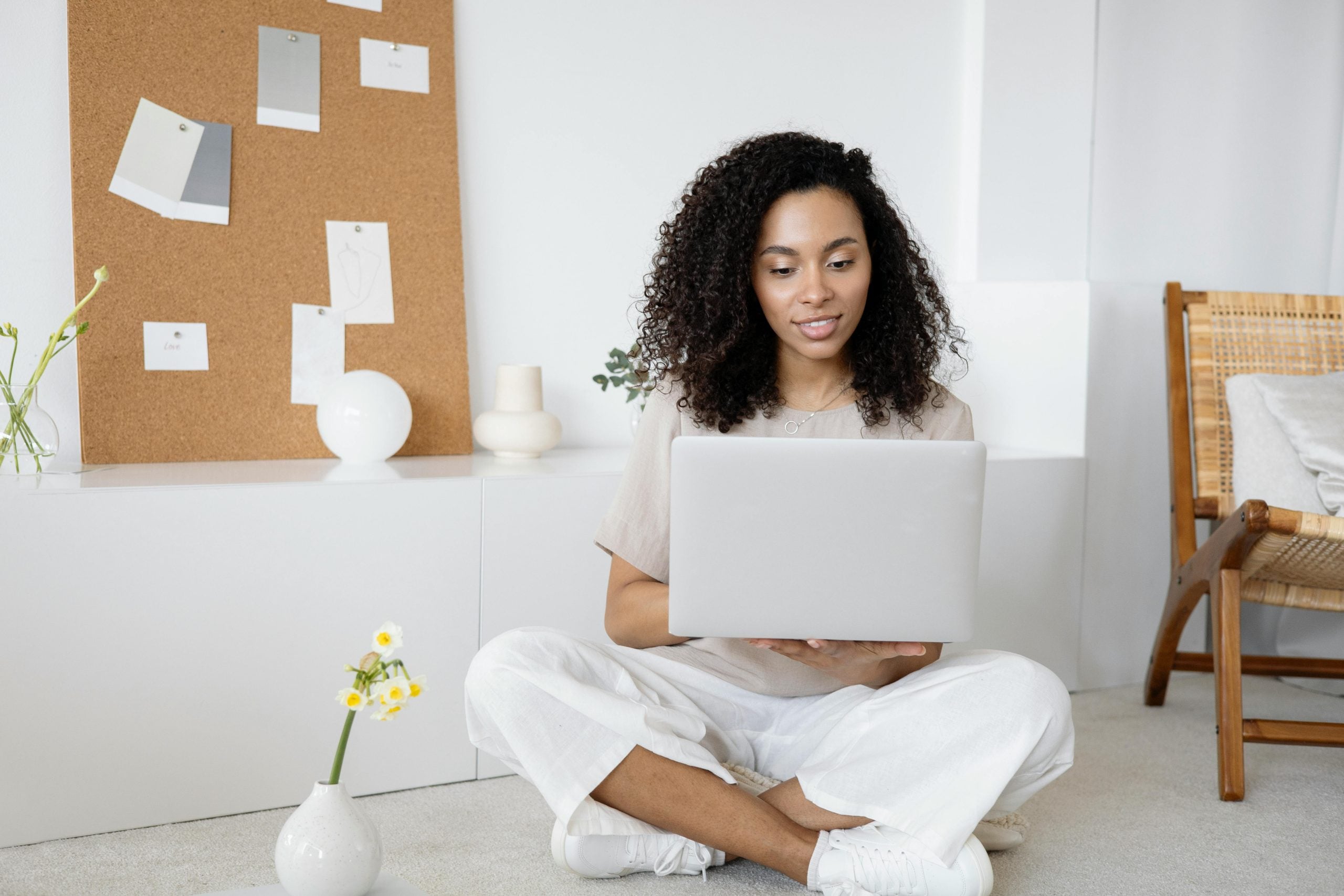 Woman sitting cross-legged working on laptop in serene, minimalist home office space