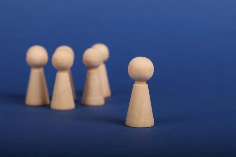 Wooden figures on blue background depicting leadership concept with one leading group.