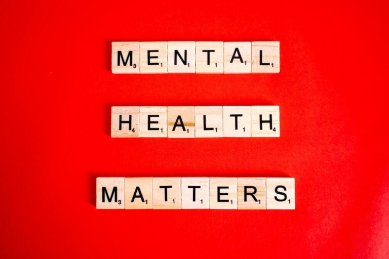 Wooden tiles spelling 'mental health matters' on vivid red background.