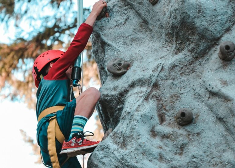 Young child rock climbing with safety gear showing courage and determination