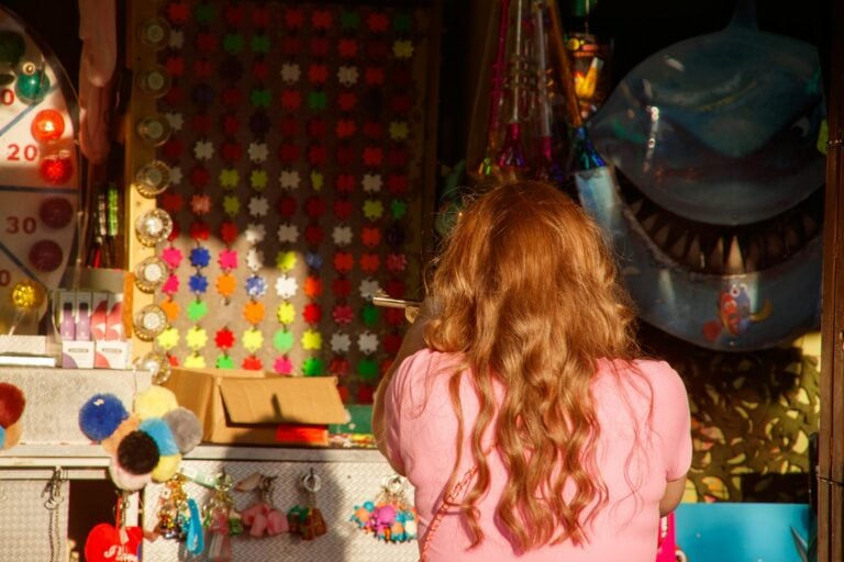 Child with red hair viewing colorful handmade crafts and decorations in shop window