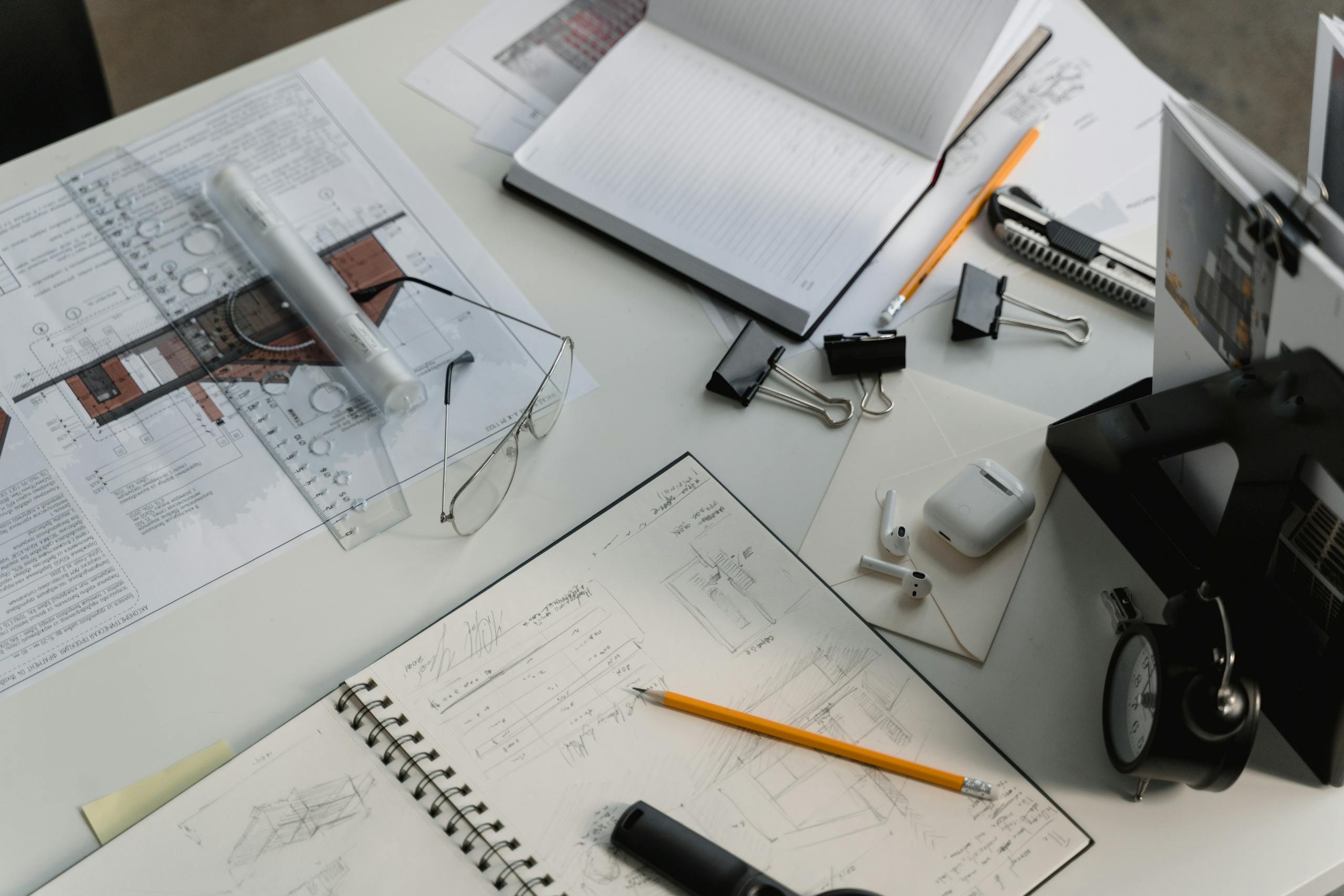 Busy architectural workspace featuring blueprints, sketches, and drafting tools.