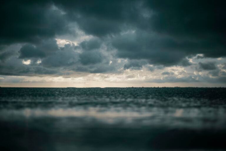 Moody seascape with dramatic dark clouds above turbulent ocean waters.