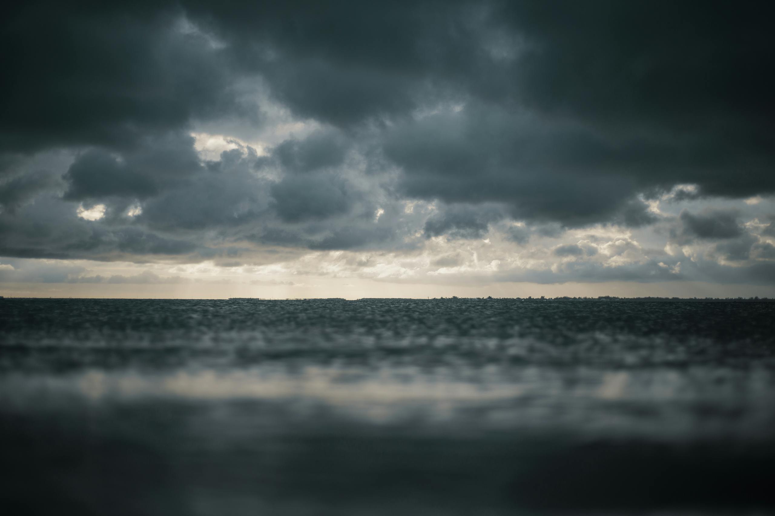 Moody seascape with dramatic dark clouds above turbulent ocean waters.