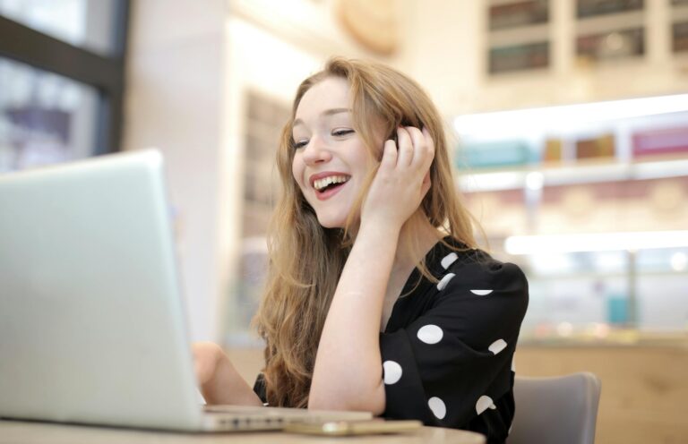 Cheerful woman engaged with her laptop in a cozy indoor setting with warm atmosphere.