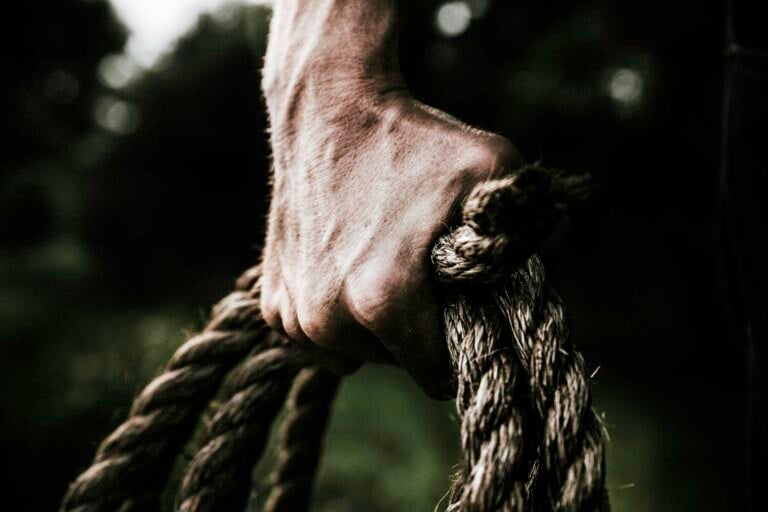 Close up of strong firm hand gripping thick rough rope showcasing strength and determination