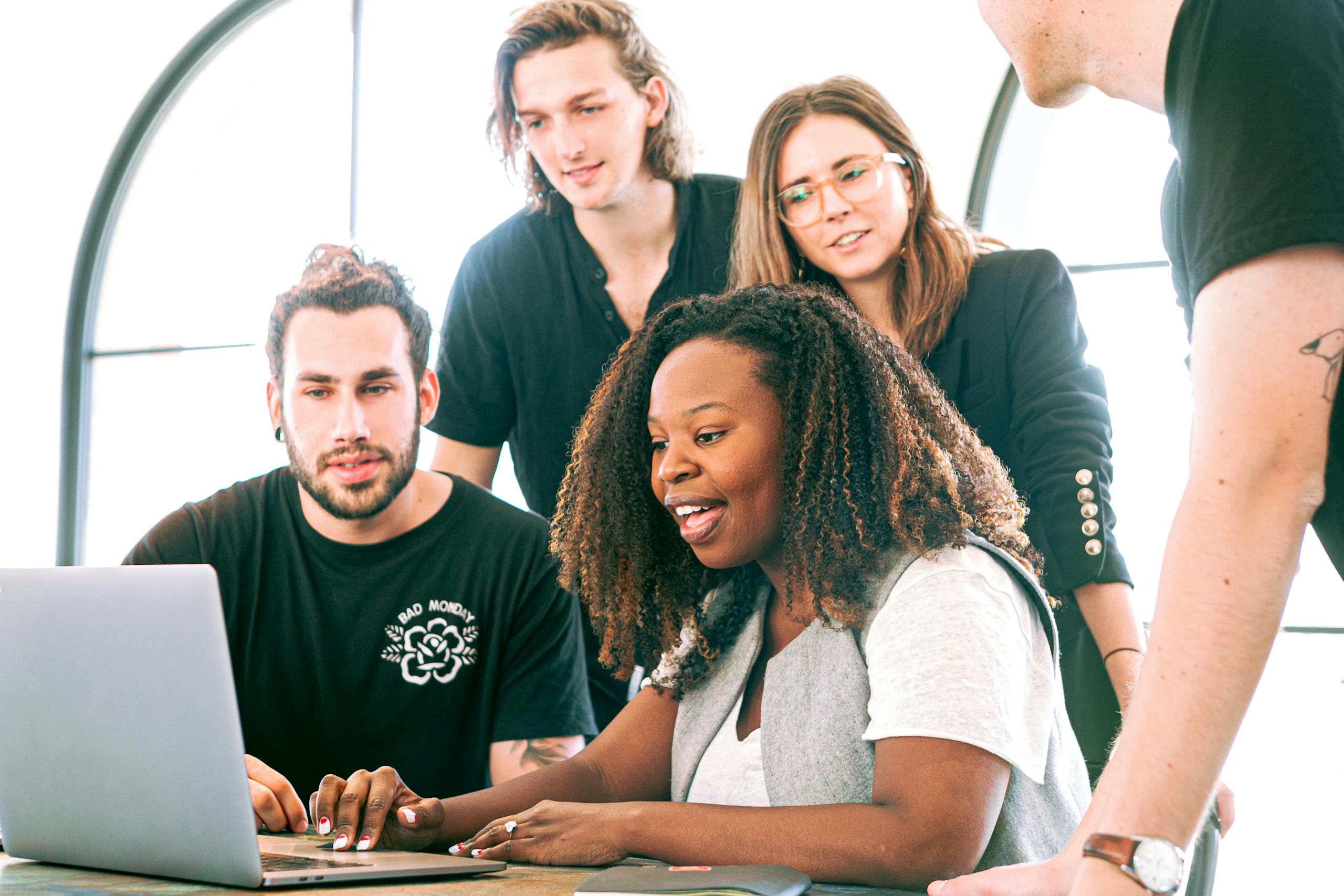 Young professionals collaborating around laptop in modern tech office