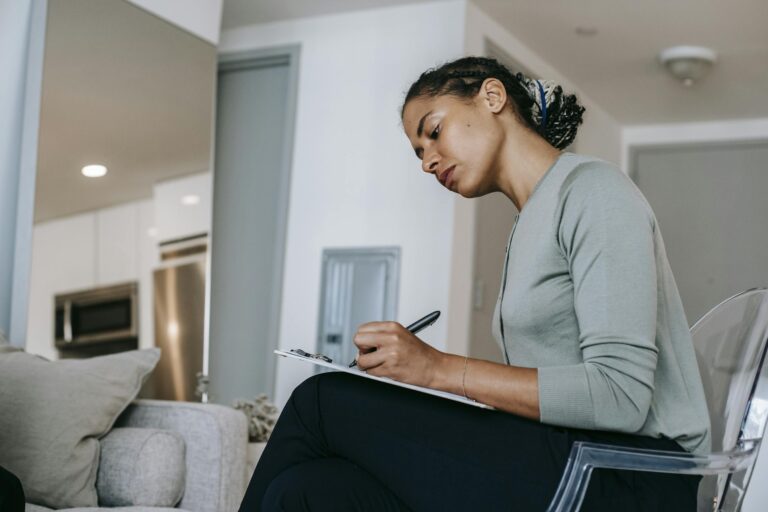 Focused woman writing on clipboard in office reflecting professional concentration