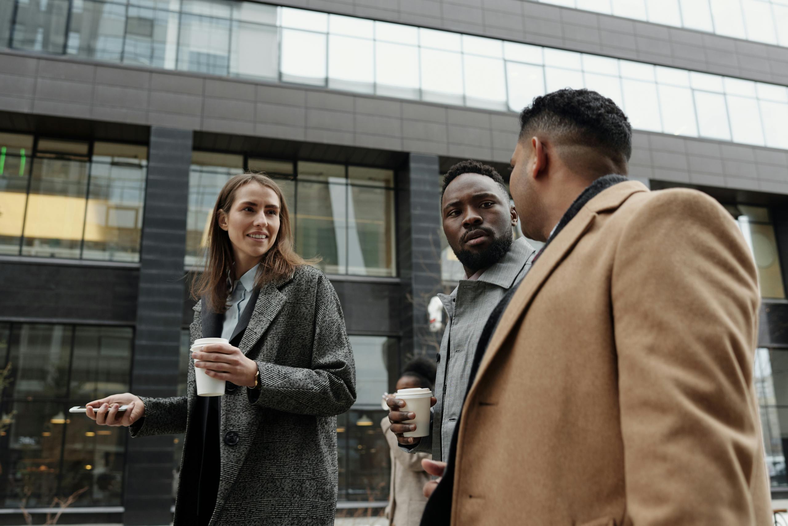 Group of diverse professionals having coffee and discussing business outdoors.