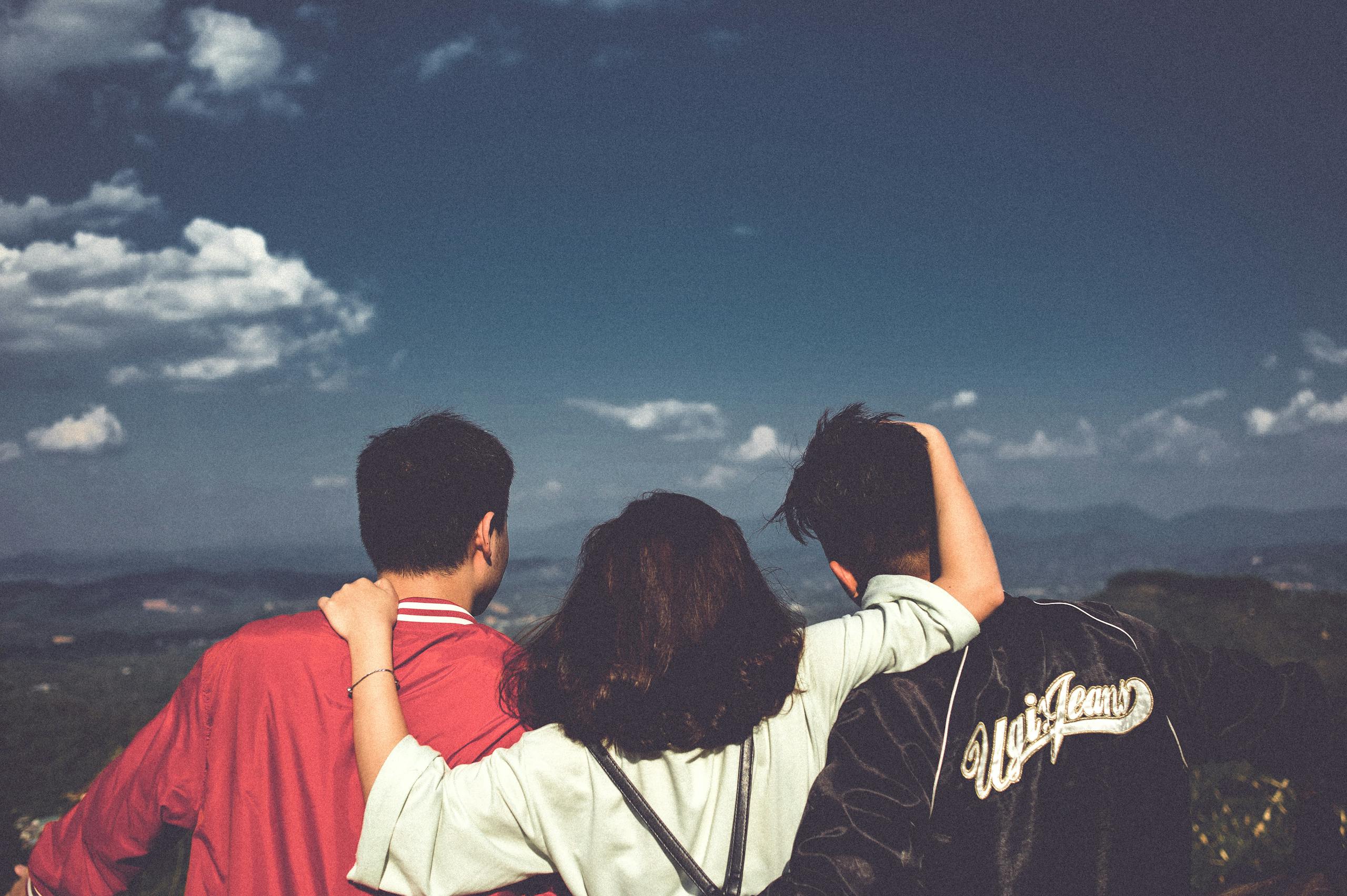 Group of three friends embracing enjoying scenic mountain view in Vietnam