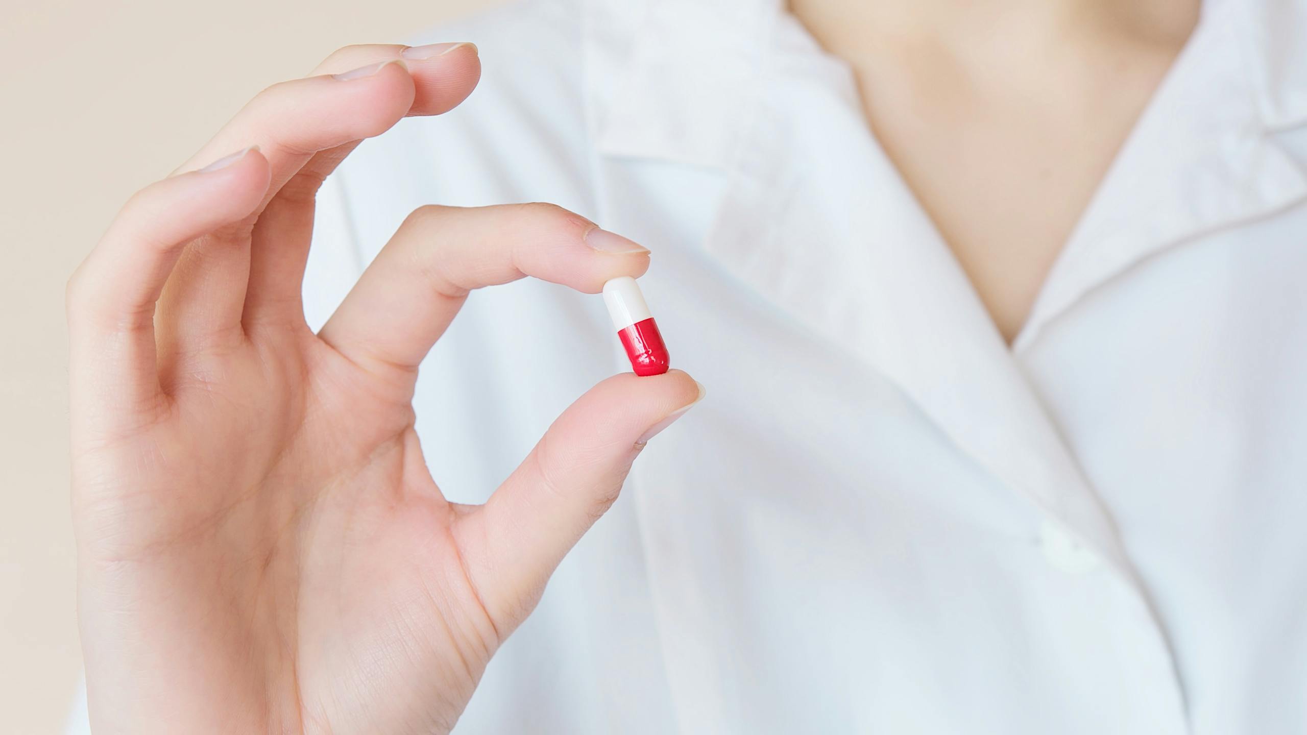 Healthcare professional holds red and white capsule exemplifying modern medicine
